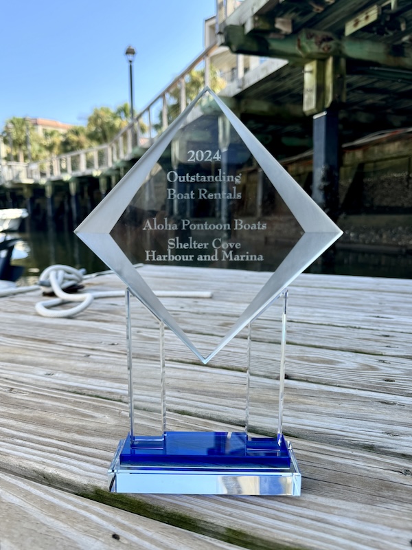 2024 Outstanding Boat Rentals Award on a clear glass trophy with marina in the background